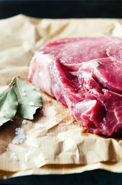 Raw ribeye steak on brown paper with salt