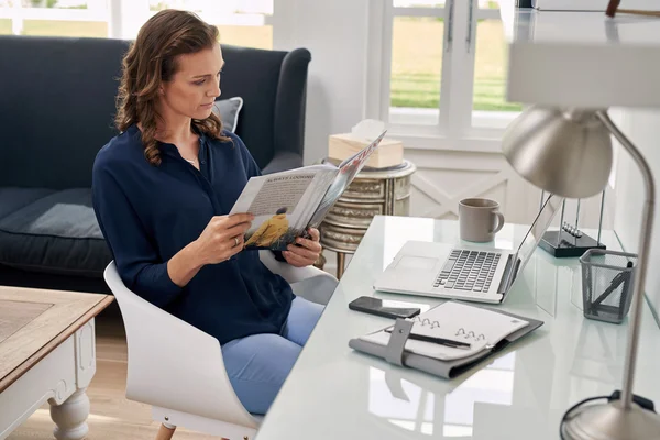 Woman reading business magazine at home office