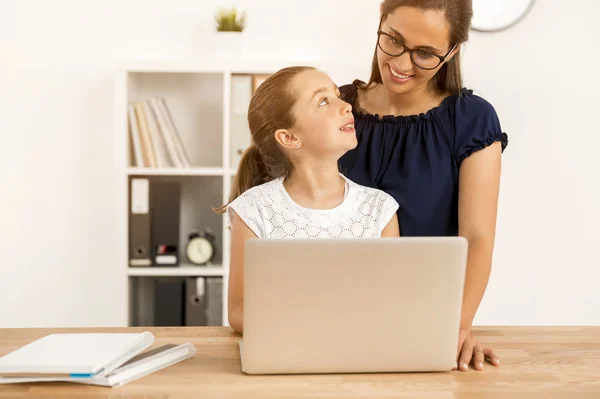 Mother helping daughter how to use computer