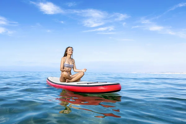 Woman relaxing over a paddle surfboard