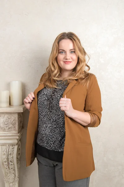 A woman in a suede jacket and pants standing by the fireplace