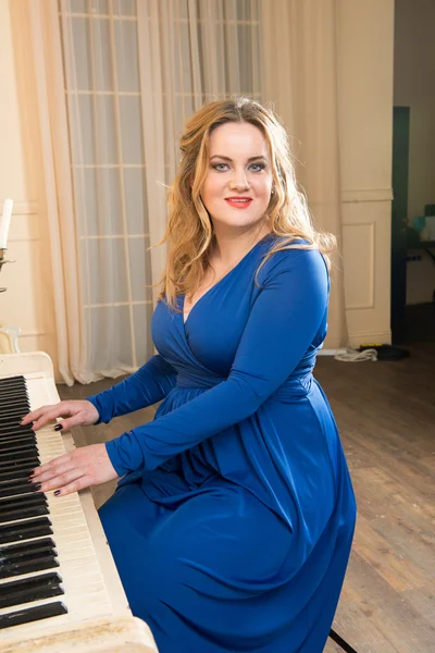 Blonde woman in a blue dress playing the piano