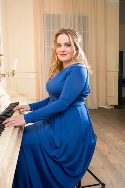 Blonde woman in a blue dress playing the piano