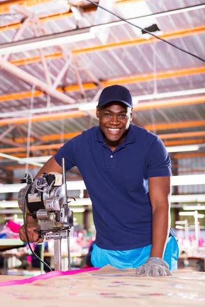 Factory worker using fabric cutter