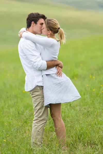 Young couple kissing on green field