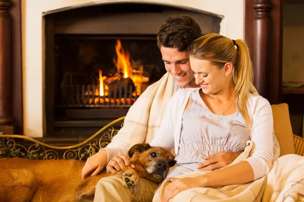 Couple sitting by fireplace with their pet dog