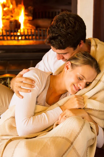 Couple wrapped in blanket at home