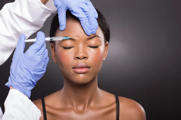 Cosmetic doctor injecting woman forehead