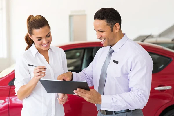 Woman buying a new car at vehicle showroom