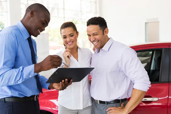 Car dealer explaining sales contract to couple