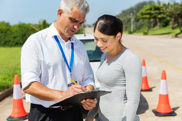 Student driver with senior instructor filling forms