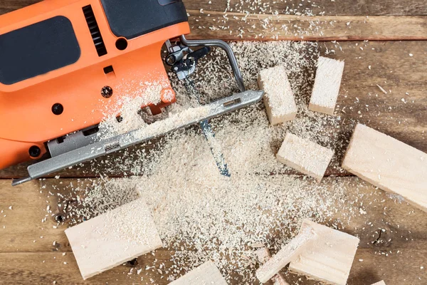 Electric jigsaw with many wooden bricks full of sawdust.