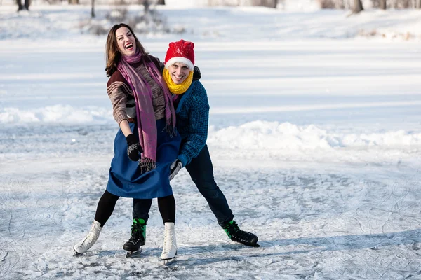 Happy couple having fun ice skating on rink outdoors.