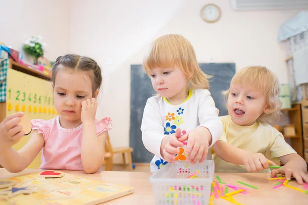 Kids group playing puzzle and other board games in kindergarten