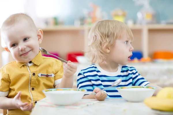 Funny children eating in kindergarten