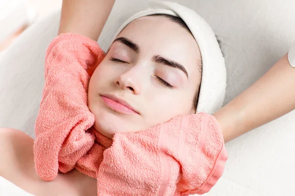 Young woman facial treatment or massage with towel