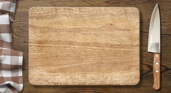 Cutting board and knife on old wood table with picnic tablecloth