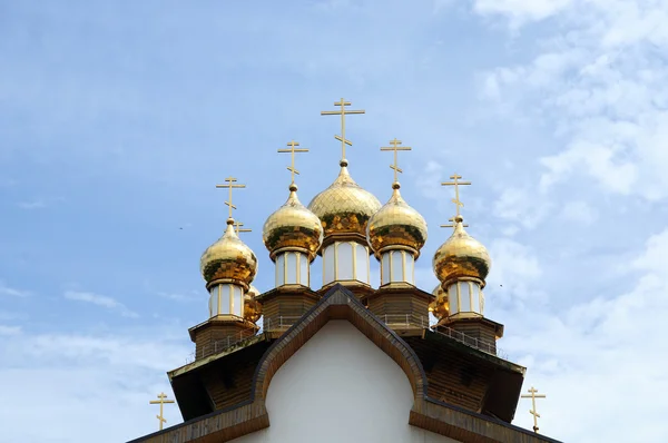 Summer sunny day of the Holy Trinity. Golden domes of the Russian Orthodox church against the blue sky.