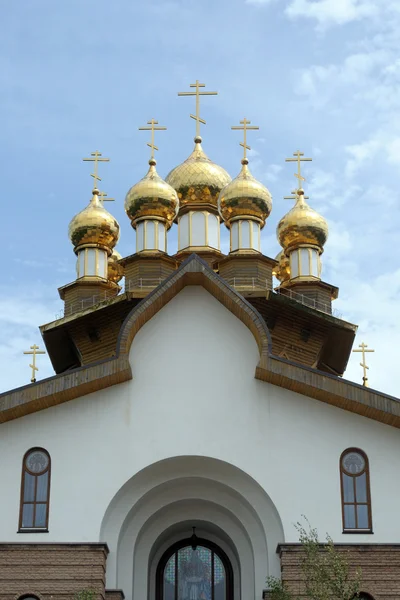 Summer sunny day of the Holy Trinity. Golden domes of the Russian Orthodox church against the blue sky.