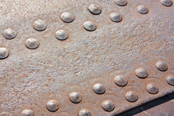 Rusty metallic plate with rivets