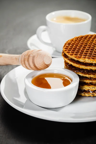 Honey waffles and coffee on ceramic background