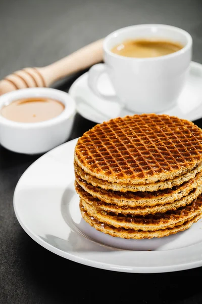 Honey waffles and coffee on ceramic background