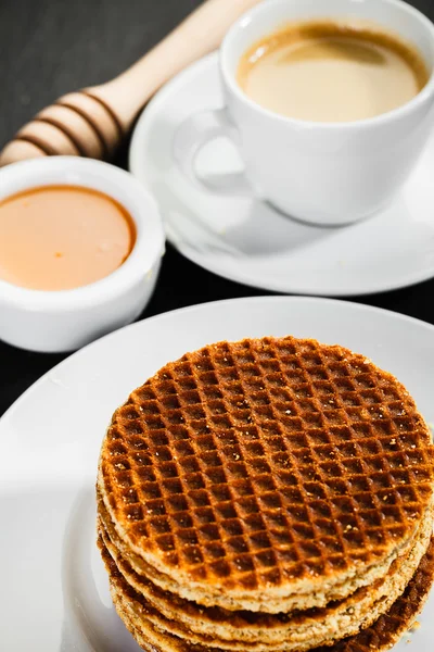 Honey waffles and coffee on ceramic background