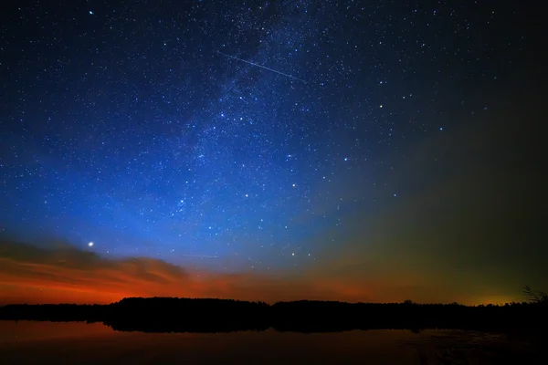 Morning dawn on a starry background sky reflected in the water o