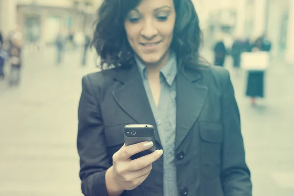 Businesswoman with smartphone walking on street. phone in focus