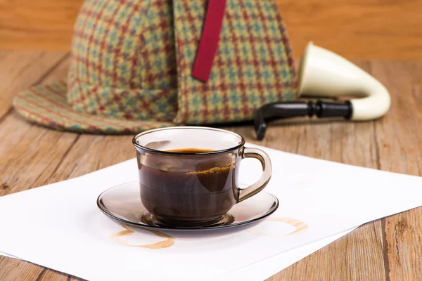 Coffee cup, paper sheets and detective hat