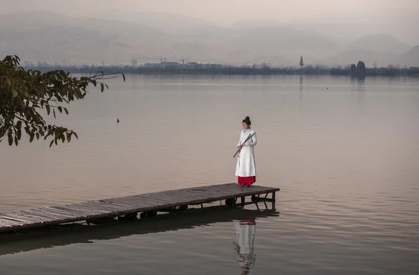 A beautiful girl standing on the bridge to play fruit music.