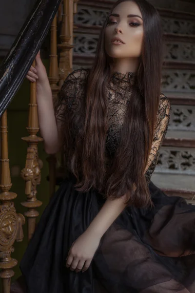 Beauty fashion woman with long hair and smokey eyes , sitting on the stair case  wearing designer stylish dress