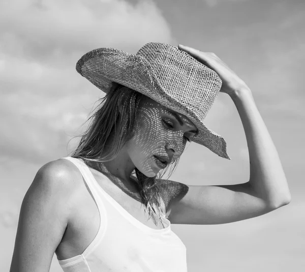 Portrait of beautiful young woman with straw hat on a sunny day  over sky and trees landscape. Black and white photo - face closeup of pretty girl with straw hat pattern shadow on her face