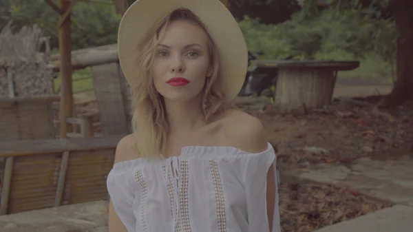 Pretty naturally looking woman in boho style fashion wearing white shirt and hat on a beautiful summer day