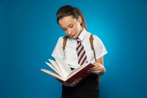Young schoolgirl reading from a class text book