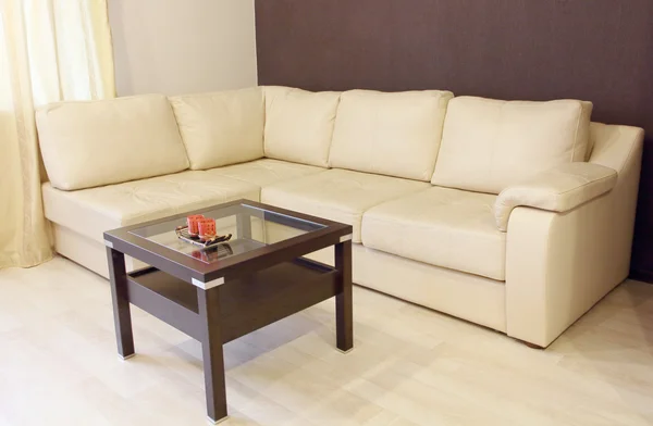Modern white corner leather sofa and wooden table.