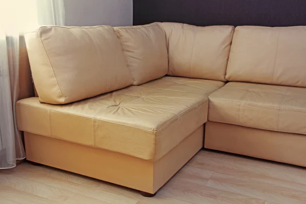 Modern beige corner leather sofa in livingroom.