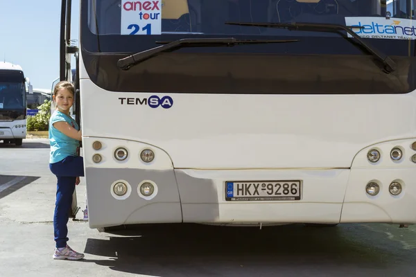 Girl posing near tourist bus with Anex Tour logo at Heraklion Airport