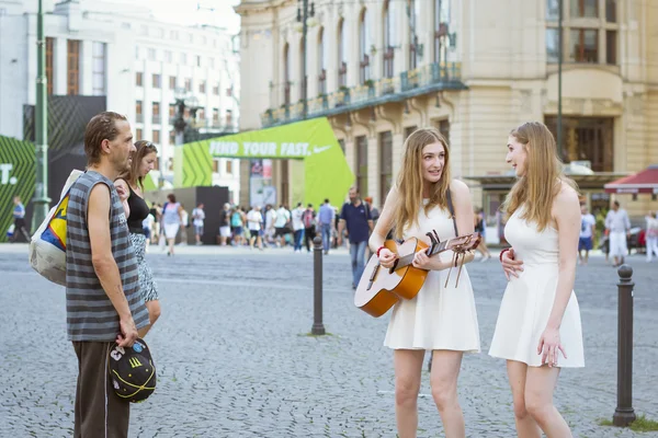 A homeless man watches as two girls-twins sing and play guitar