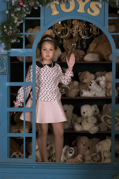 Girl portrays a porcelain doll in the window with plush bears