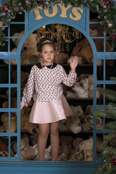 Girl portrays a porcelain doll in the window with plush bears