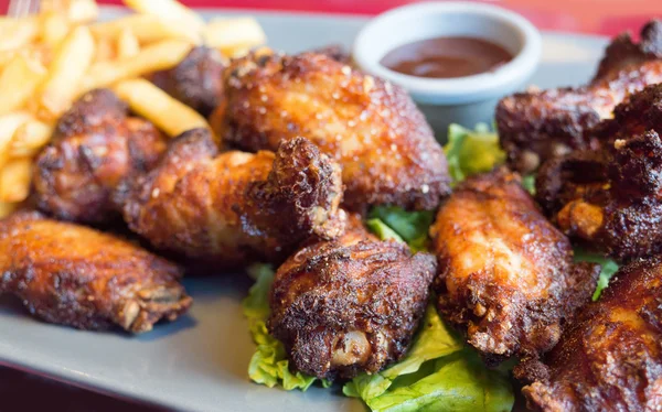 Chicken wings with sauce and golden French fries potatoes