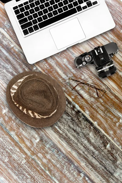 Computer notebook camera and hat on wooden desk