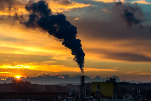 Sunrise silhouette of smoking factory