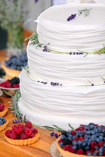 Wedding cake on wooden background with blueberries raspberries a