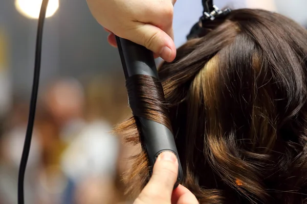 Hairdresser turns hair curling iron of young girl