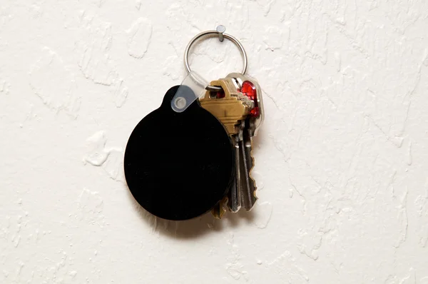 Three keys on wall with round blank black fob