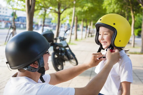 Father trying to wear a bike helmet to his daughter