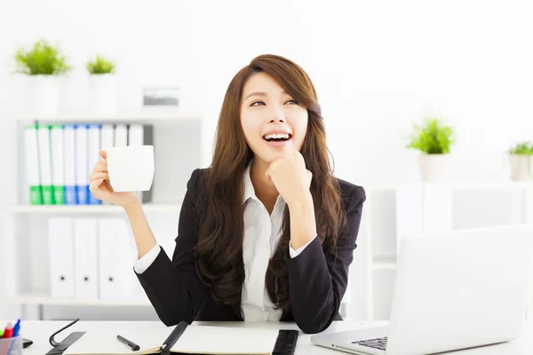 Beautiful young business woman drinking coffee in office