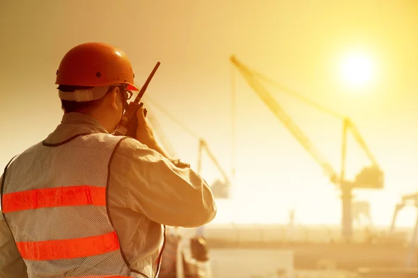 Worker with large crane site and sunset background